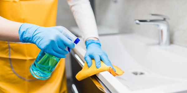 Picture showing an expert domestic cleaner cleaning a bathroom sink